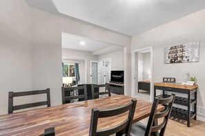 Un coin repas avec une table et des chaises en bois, un téléviseur et un bar avec un panneau indicateur.