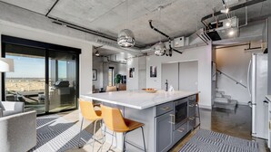 Eine moderne Küche mit einer großen Kochinsel, Barhocker und Blick durch eine Glastür.