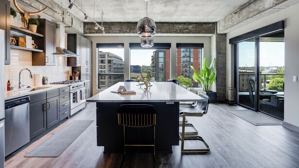 Una cucina moderna con una grande isola, elettrodomestici in acciaio inossidabile e vista sulla città attraverso ampie finestre.