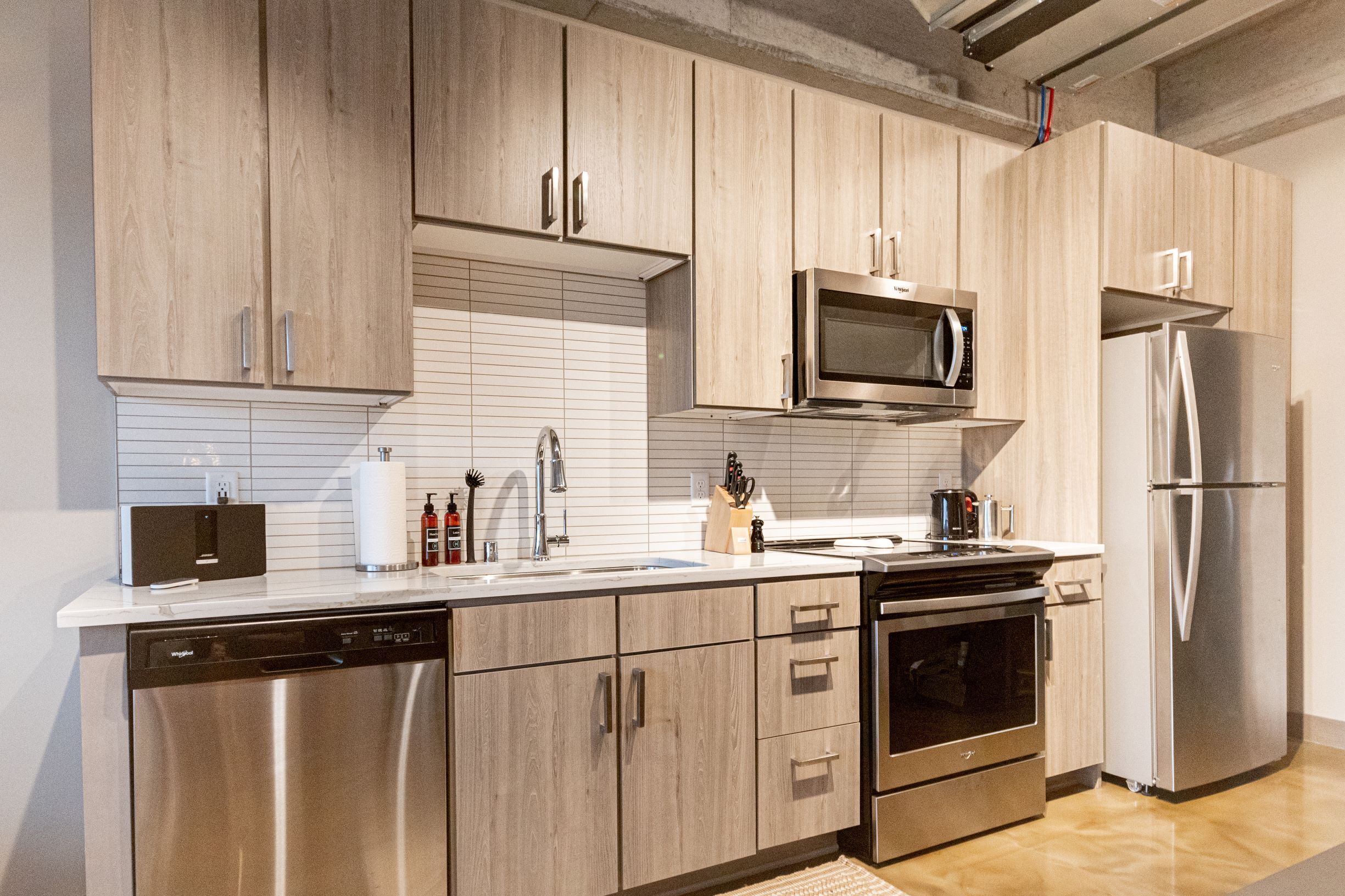 A modern kitchen with wooden cabinets, stainless steel appliances, and a dishwasher.