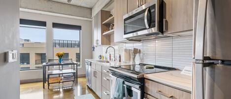 A modern kitchen with stainless steel appliances, wooden cabinets, and a dining area with a view.