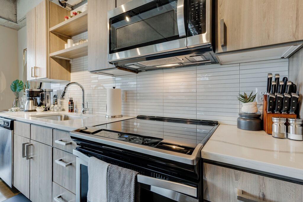 Une cuisine moderne dotée d’appareils électroménagers en acier inoxydable, de meubles en bois et d’un dosseret de carrelage blanc.