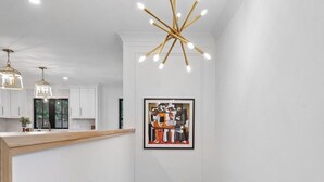 Une cuisine moderne avec des armoires blanches, un plan de travail en bois et des luminaires suspendus.