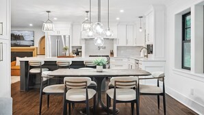 Une cuisine moderne avec des meubles blancs, un îlot central et un coin repas équipé de six chaises.