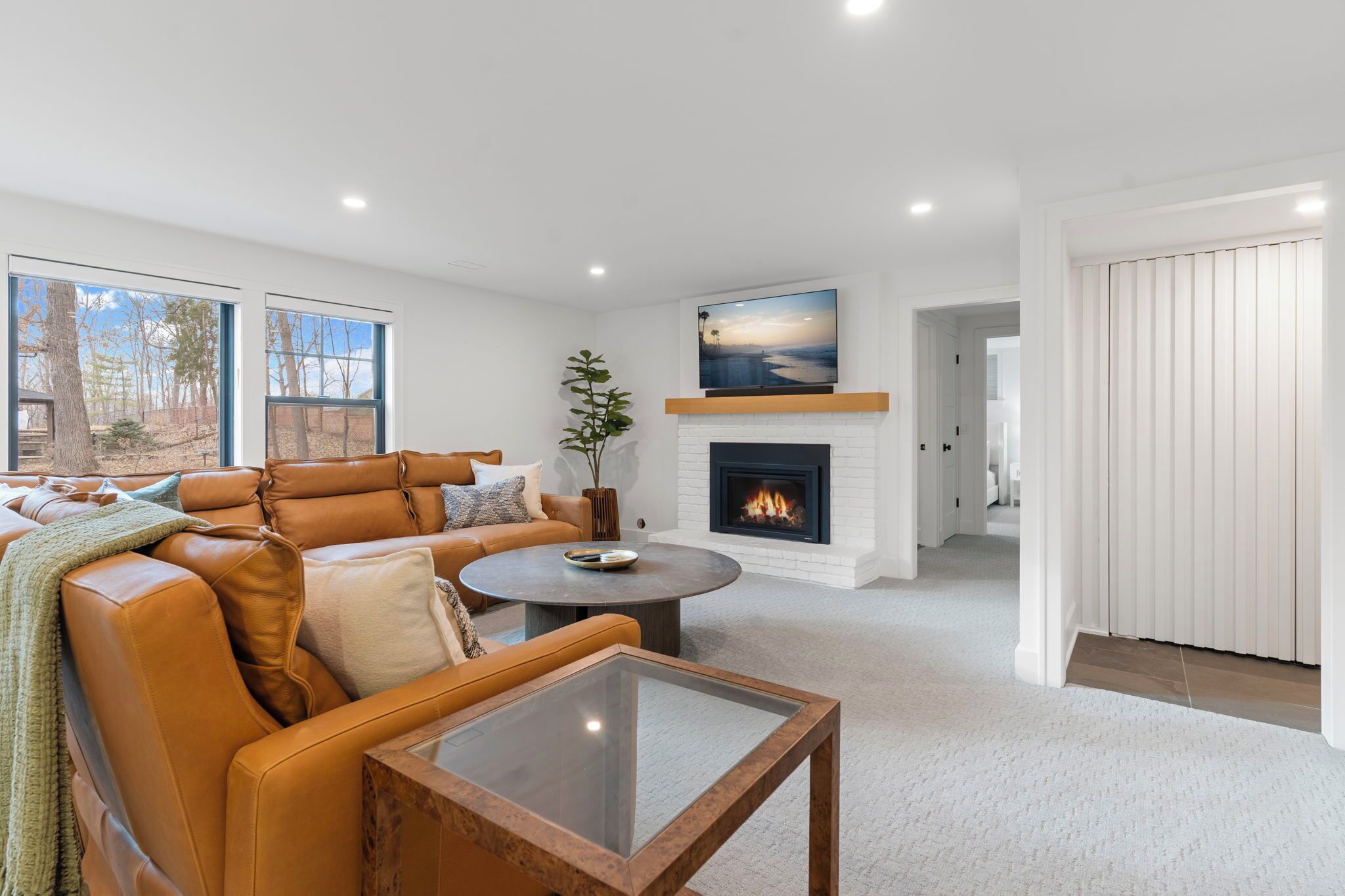 A modern living room with a leather sofa, a fireplace, and a large window.