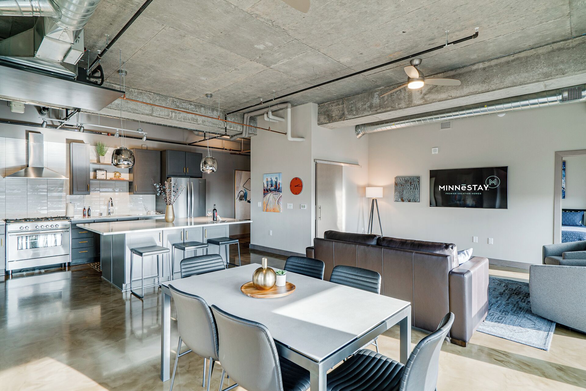 A modern kitchen with a central island, bar seating, and a dining area with a table and chairs.