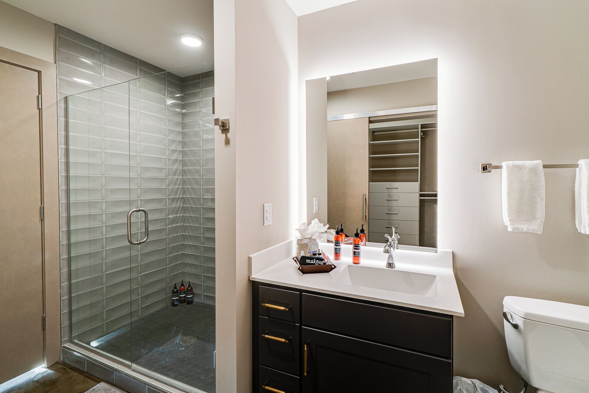 A modern bathroom with a glass shower enclosure, a white sink with a vanity, and a toilet.