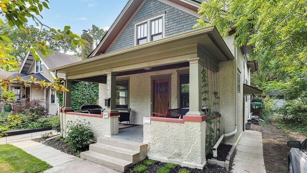 A two-story house with a covered porch, a small garden, and a mailbox. - Pillsbury Hideaway (Minneapolis)