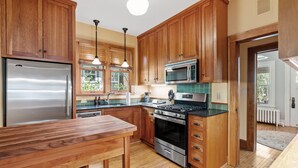 A modern kitchen with wooden cabinets, stainless steel appliances, and a wooden dining table. - Pillsbury Hideaway (Minneapolis)
