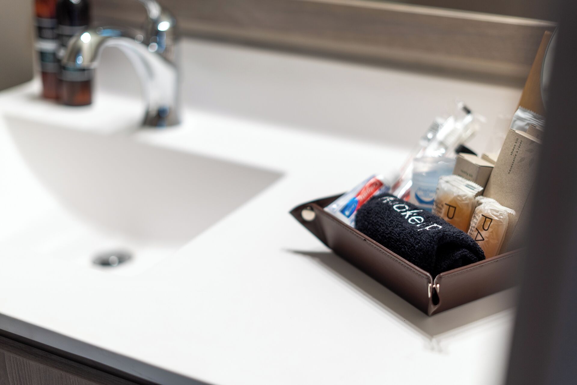 Un lavabo de salle de bain avec des articles de toilette disposés dans un plateau marron.