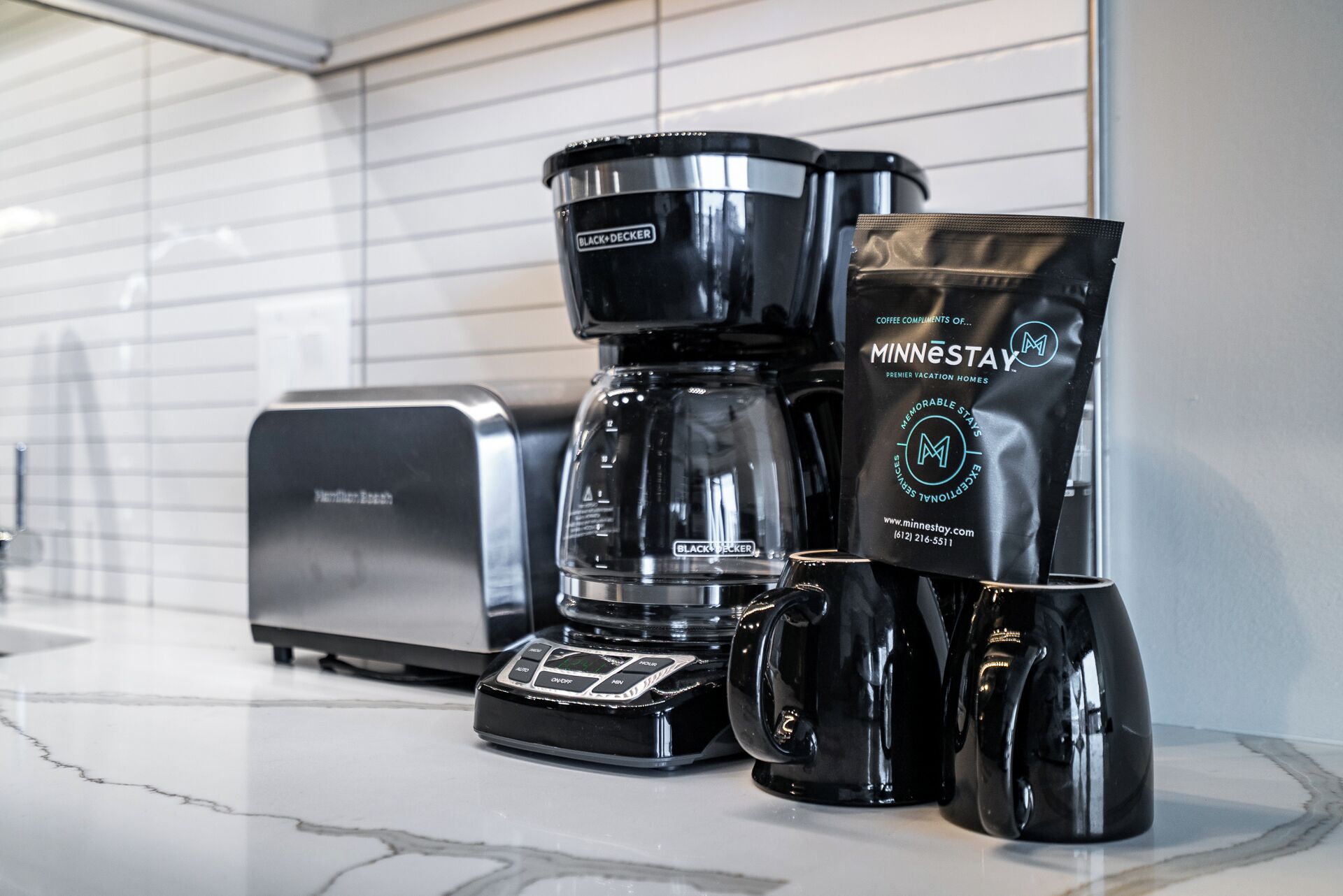 Eine Kaffeemaschine, ein Toaster und eine Kapsel für Kaffee auf einer Arbeitsplatte.