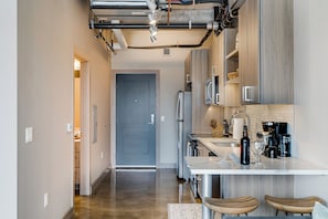 A modern kitchen with stainless steel appliances, a built-in oven, and a wooden island with bar stools.