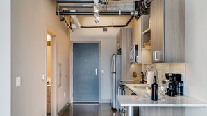 A modern kitchen with stainless steel appliances, a white countertop, and wooden bar stools. - Sable 803 - Alcove (Minneapolis)