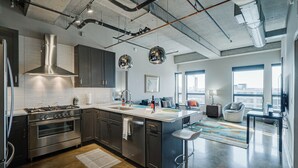 A modern kitchen with stainless steel appliances, a large island, and a bar area. - Sable 805 - Two Bedroom (Minneapolis)
