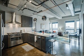 A modern kitchen with stainless steel appliances, a large island, and a bar area. - Sable 805 - Two Bedroom (Minneapolis)