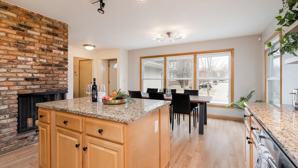 A spacious kitchen with a granite countertop, wooden cabinets, and a brick accent wall. - D. The Retreat at Linden Hills (Minneapolis)