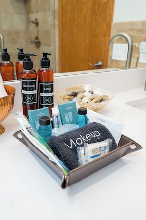 Un meuble-lavabo de salle de bain avec des articles de toilette, notamment du savon liquide pour les mains, une lotion et un savon en pain.