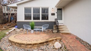 A house with a brick patio, two chairs, and a potted plant. - D. The Retreat at Linden Hills (Minneapolis)