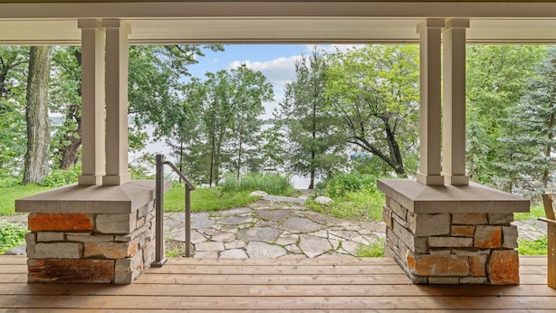 A covered outdoor area with stone pillars and a stone pathway leading to a scenic view. - Turtle Lake Cottage (Shoreview)