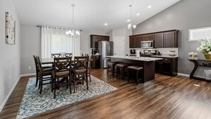 A modern kitchen with dark wood cabinets, stainless steel appliances, and a central island. - Savanna Grove (Blaine)