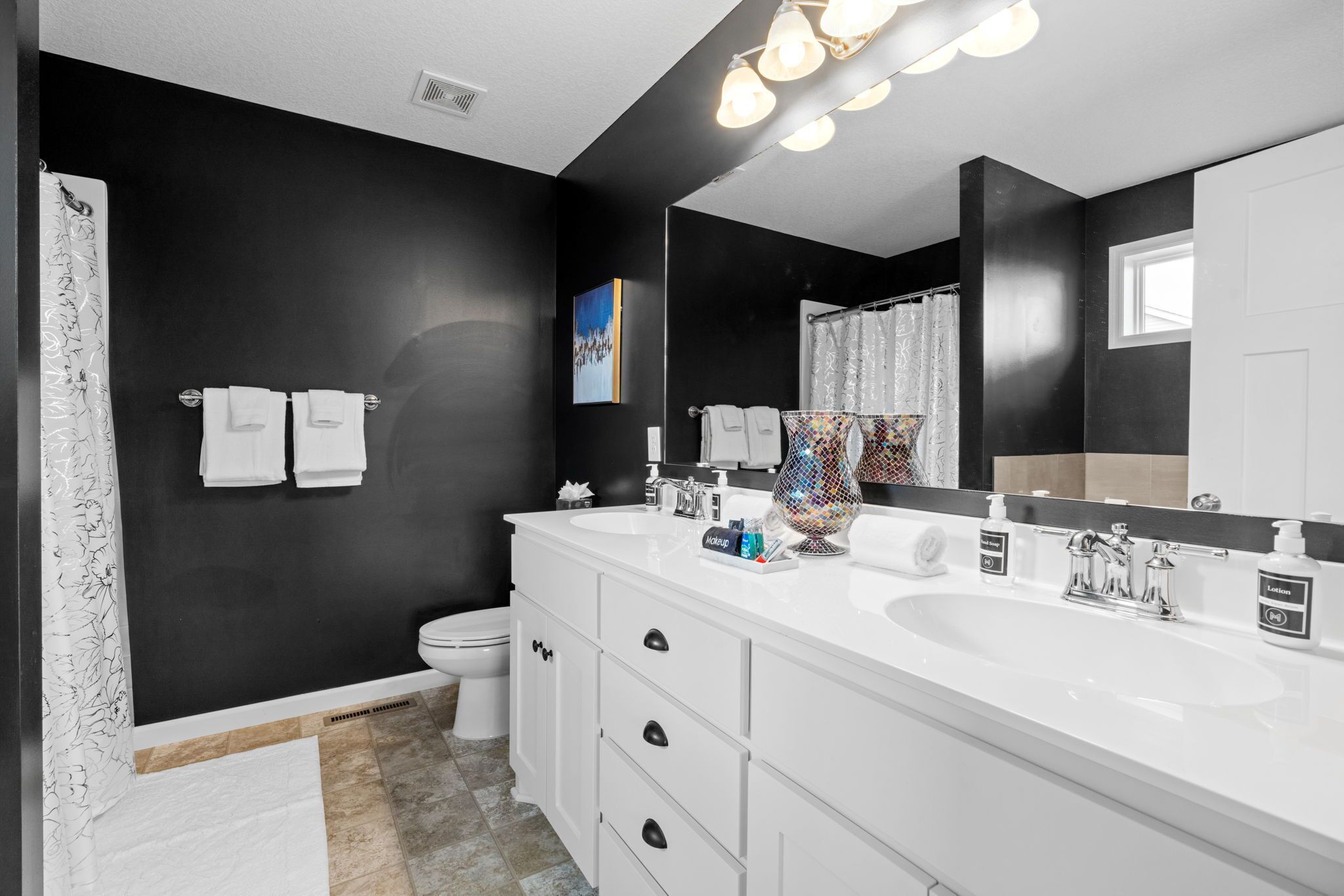 A modern bathroom with two sinks, a large mirror, and a shower area.