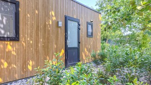 A modern wooden building with a black door and two windows, surrounded by lush greenery. - Nice home in Oosterwolde with WiFi (Oosterwolde)