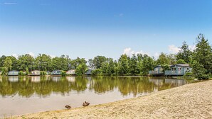 A lakeside property with multiple cabins, a sandy beach, and ducks on the shore. - 2 bedroom awesome home in Oosterwolde (Oosterwolde)