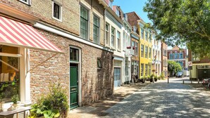 Una calle adoquinada flanqueada por edificios coloridos, una puerta verde y mesas al aire libre.