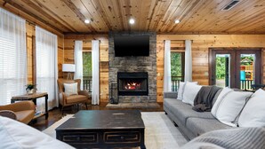 L’intérieur d’un chalet confortable, avec une cheminée en pierre, des murs en bois, un canapé et une table basse.