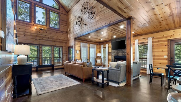 Un intérieur de cabane spacieux, doté d’une cheminée, de murs en bois et de grandes fenêtres.
