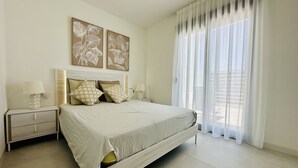 Une chambre à coucher comprenant un lit, des tables de chevet, une lampe et deux œuvres d’art murales.