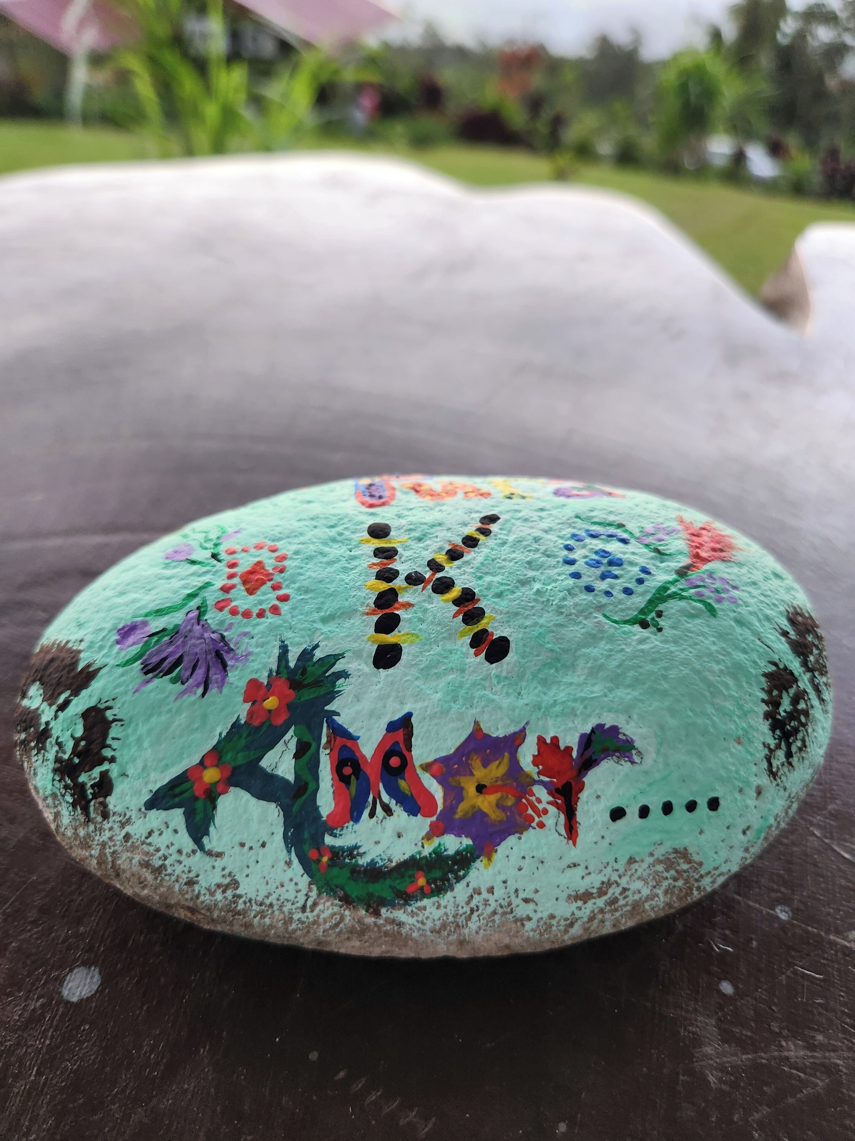 A painted rock with floral and abstract designs.