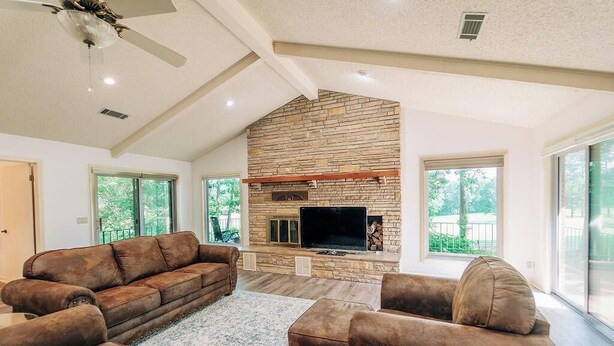 A spacious living room with a stone fireplace, leather sofas, and a flat-screen TV.