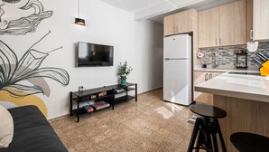 A modern kitchen with a built-in fridge, wooden cabinets, a black countertop, and a small bar stool. - Oasis Condado Pool Parking Beach Steps Away (San Juan)