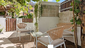 An outdoor seating area with wicker chairs and a glass table, surrounded by a brick floor and a concrete wall. - Oasis Condado Pool Parking Beach Steps Away (San Juan)