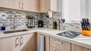 A modern kitchen with wooden cabinets, a stainless steel sink, a coffee maker, and a knife block. - Oasis Condado Pool Parking Beach Steps Away (San Juan)