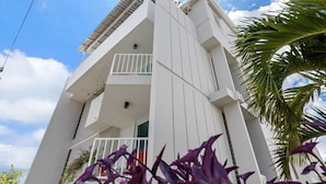 A white building with a balcony and a palm tree in the foreground. - Ocean Park Oasis Steps to Beach Private Parking (San Juan)