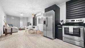 A modern kitchen with a built-in refrigerator, oven, and dining area with a table and chairs. - Ocean Park Oasis Steps to Beach Private Parking (San Juan)
