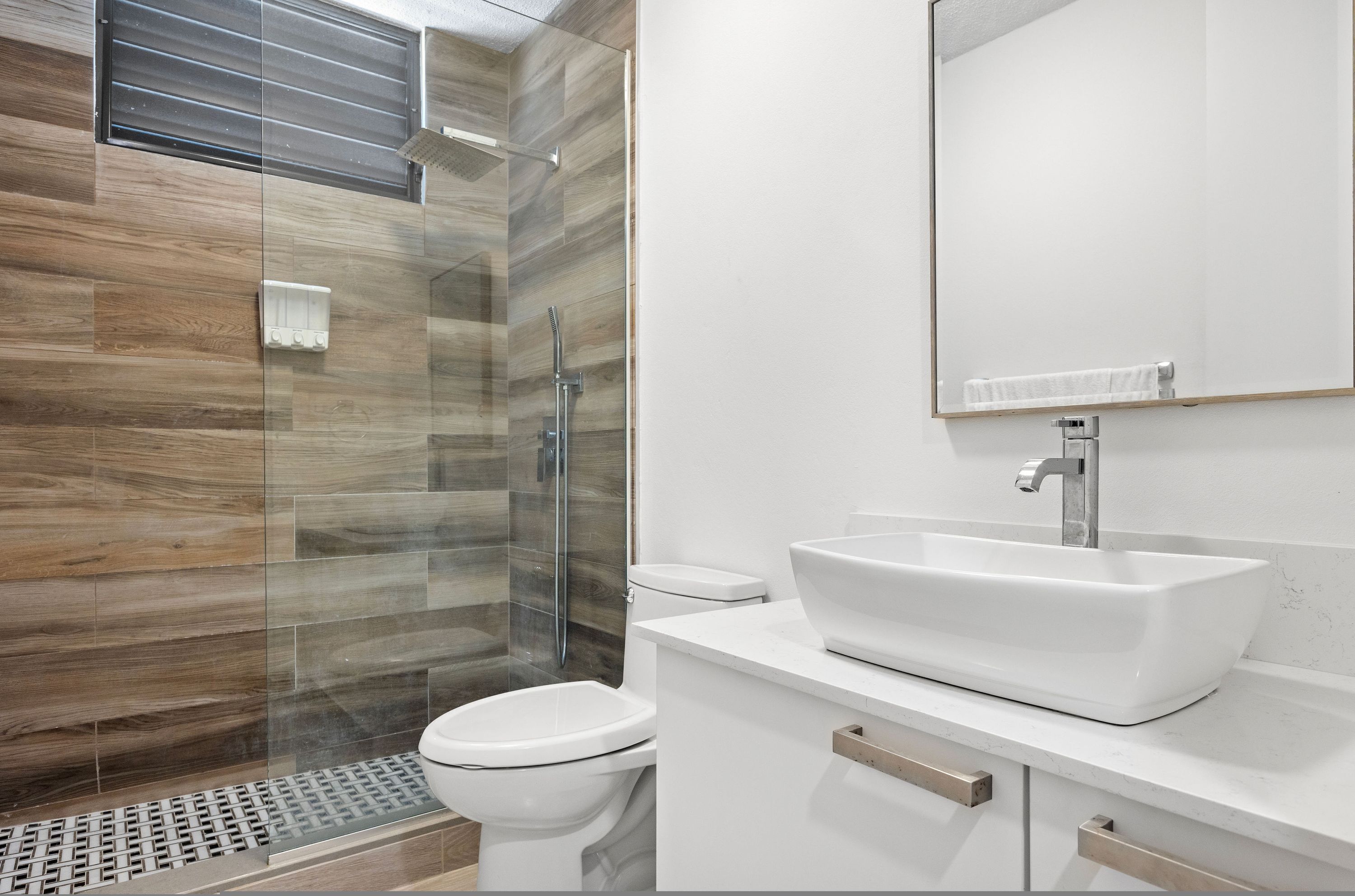 A modern bathroom with a glass-enclosed shower, a white sink, and a toilet.