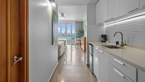 A modern kitchen with a countertop and sink, a dining area with a table and chairs, and a bedroom with a bed and window. - Oceanfront Old San Juan Charm Private Rooftop (San Juan)