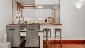 Una cocina moderna con armarios blancos, encimera de madera y una barra con taburetes.