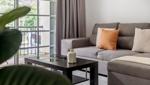 Una sala de estar moderna con un sofá gris, una mesa de centro negra y una planta en maceta.