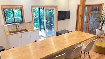 A modern kitchen with a wooden countertop, white cabinets, a sink, and a large window.
