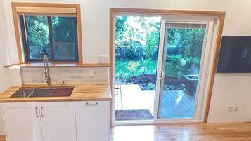 A kitchen with a wooden countertop, a sink, and a window overlooking a garden.