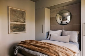 Ein Schlafzimmer mit einem Bett, einem großen Spiegel und einem Gemälde an der Wand.