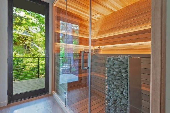 Un sauna avec des parois en bois, une porte en verre et un mur en pierre.