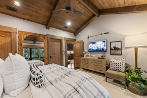 A bedroom with a bed, wooden wardrobe, and a television on the wall.