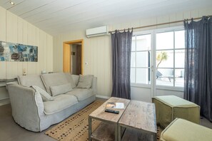 A living room with a sofa, a coffee table, and a window with curtains. - Mv Lodge (La Couarde-sur-Mer)