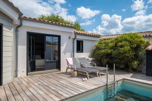 A poolside area with a wooden deck, a small pool, and two lounge chairs. - Mv Lodge (La Couarde-sur-Mer)