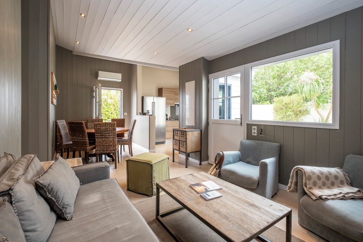 A spacious living area with a sofa, armchairs, a coffee table, and a dining area with chairs and a table.